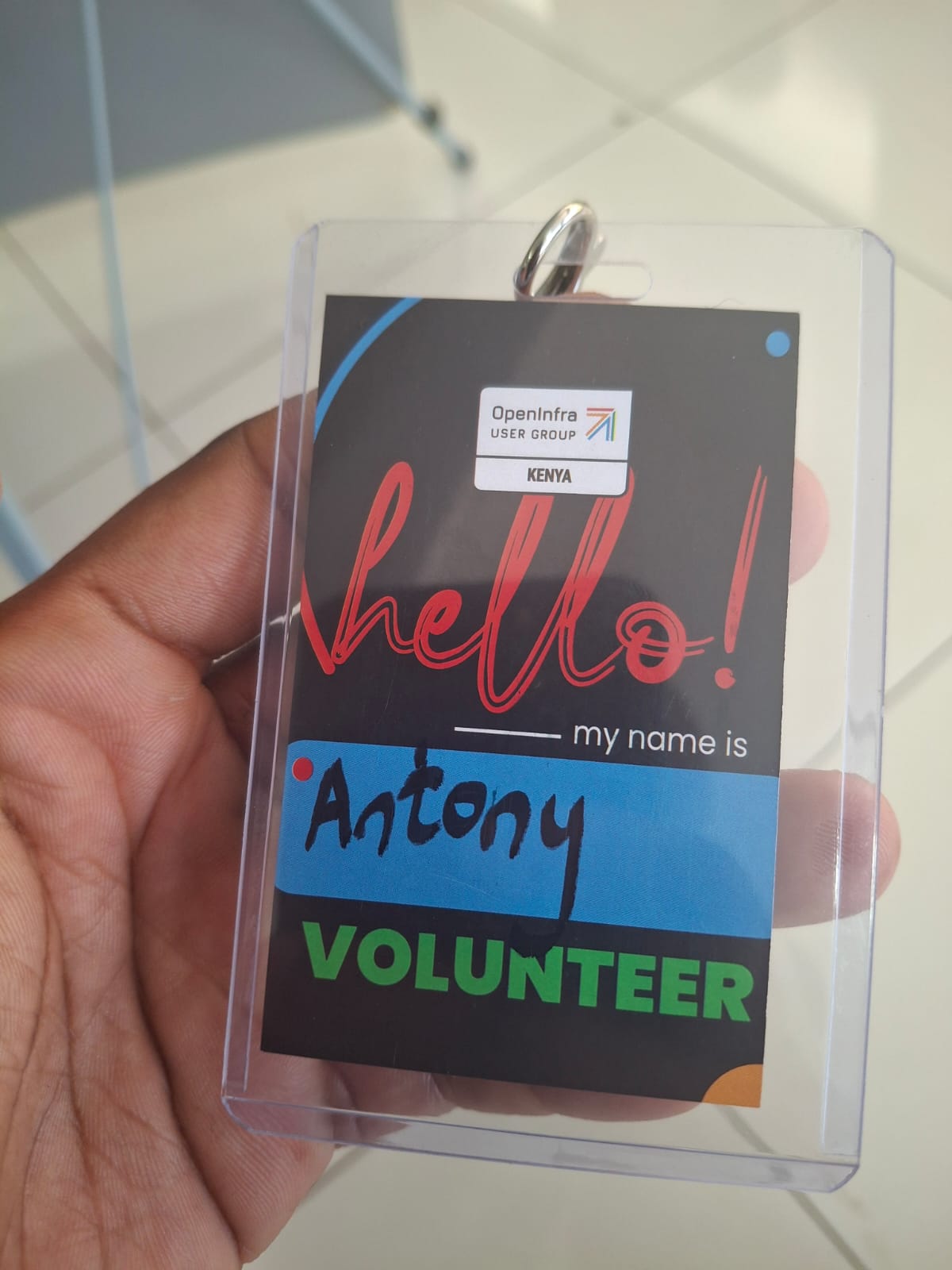 A handwritten OpenInfra Kenya volunteer nametag in a clear plastic holder